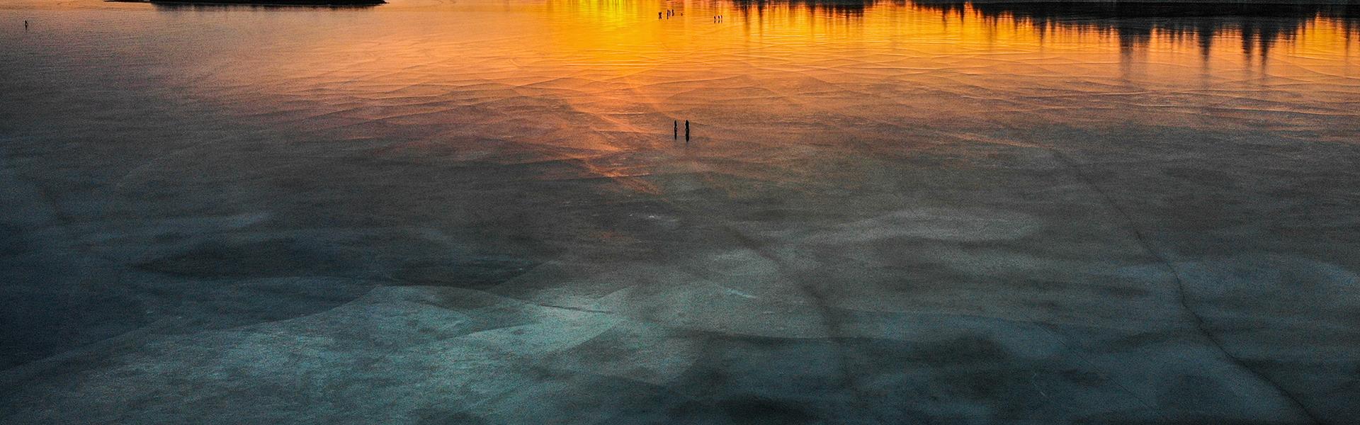 Aerial view of frozen Dragon Lake during a vibrant sunset